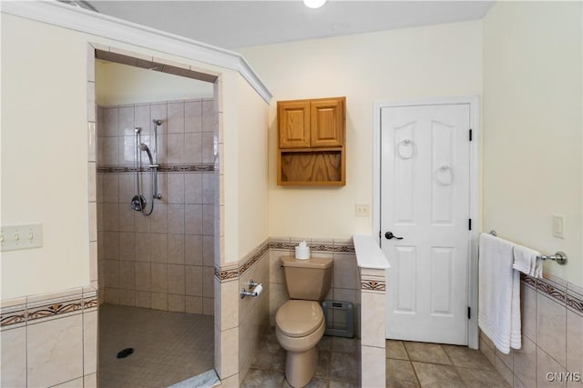 bathroom featuring tile walls, tiled shower, tile patterned floors, and toilet