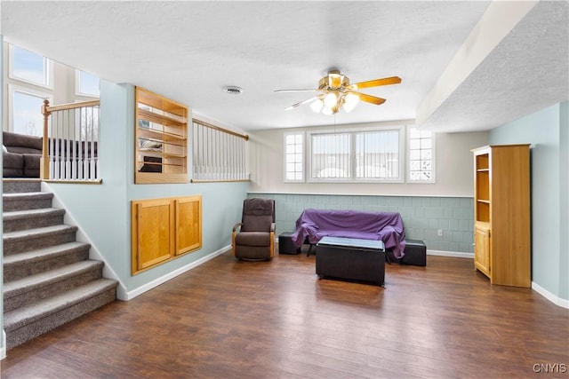 living area featuring a textured ceiling, ceiling fan, and dark wood-type flooring