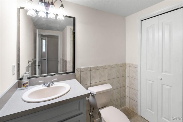 bathroom featuring toilet, vanity, and tile walls