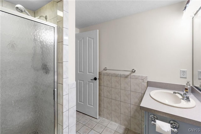 bathroom with an enclosed shower, vanity, tile patterned flooring, and a textured ceiling