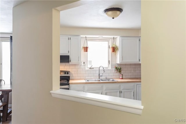 kitchen featuring white cabinetry, stove, decorative backsplash, and sink