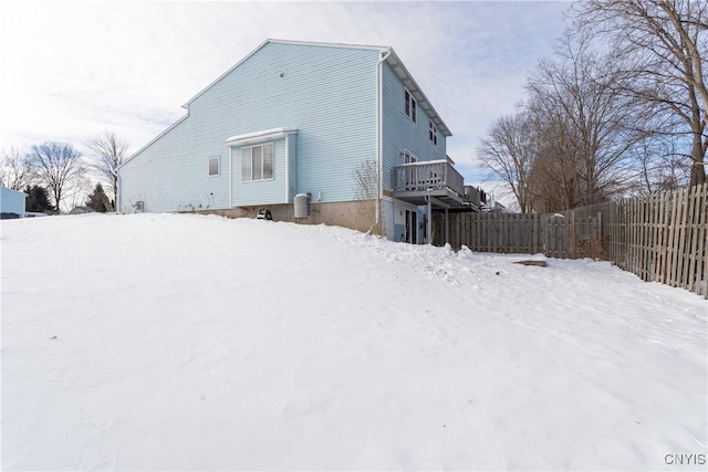 snow covered back of property featuring a deck