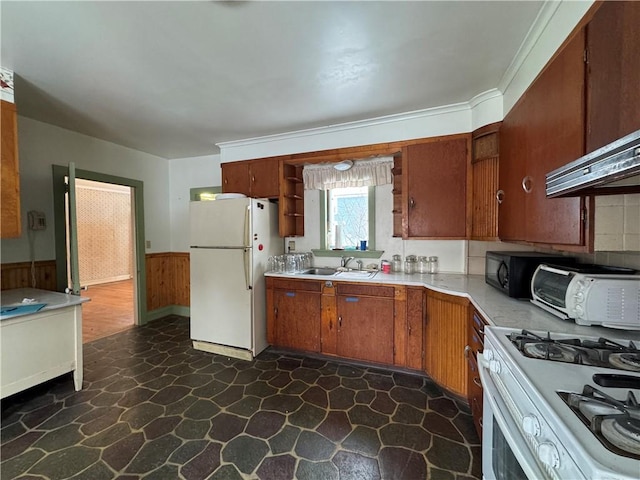 kitchen with white appliances, wooden walls, and sink