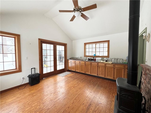 kitchen featuring light hardwood / wood-style floors, a healthy amount of sunlight, a wood stove, and ceiling fan