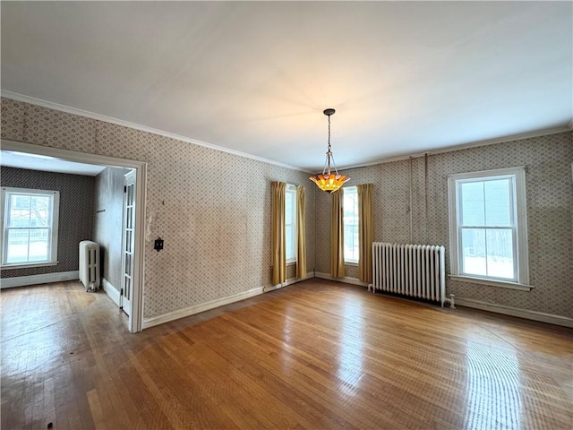 unfurnished room with hardwood / wood-style floors, crown molding, plenty of natural light, and radiator