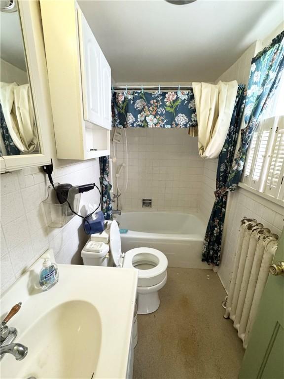 full bathroom featuring sink, shower / bath combo, radiator heating unit, and toilet