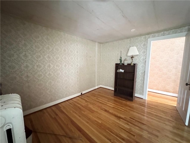 unfurnished room featuring radiator and hardwood / wood-style flooring