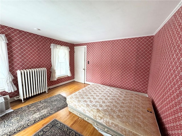 bedroom featuring crown molding, radiator, and light hardwood / wood-style flooring