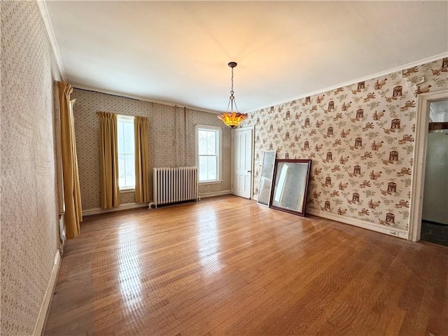 spare room with ornamental molding, radiator, and light hardwood / wood-style flooring