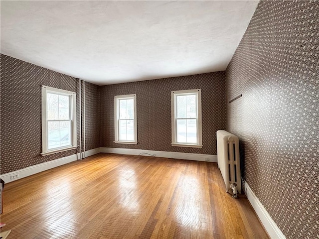 empty room featuring hardwood / wood-style flooring and radiator heating unit