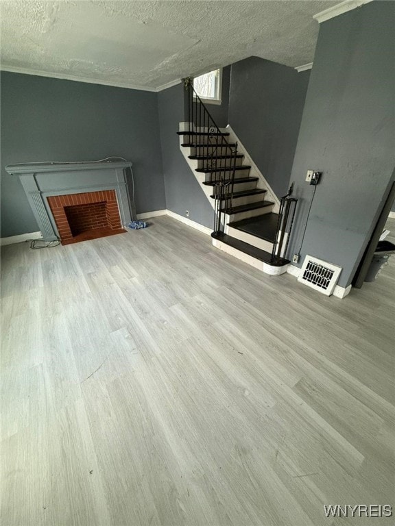 unfurnished living room with a textured ceiling, ornamental molding, and hardwood / wood-style flooring