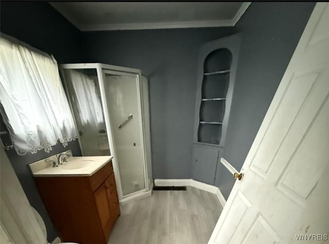 bathroom featuring built in features, an enclosed shower, vanity, and hardwood / wood-style flooring