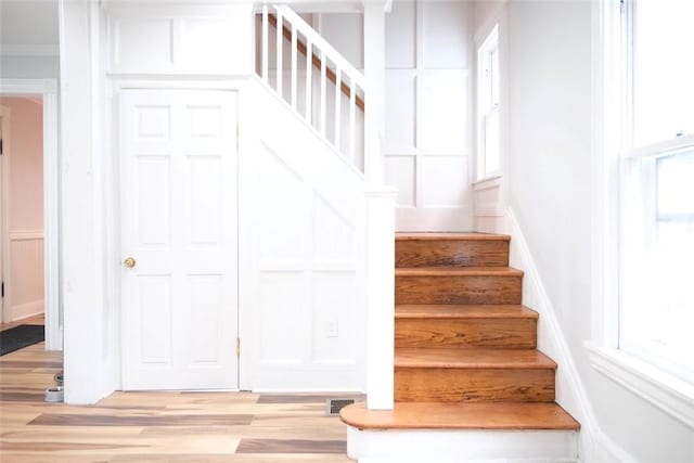 stairway with crown molding and wood-type flooring