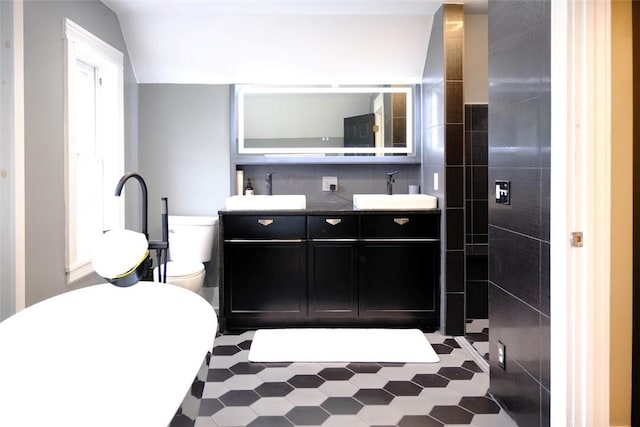 bathroom with toilet, tile patterned floors, vanity, and tile walls