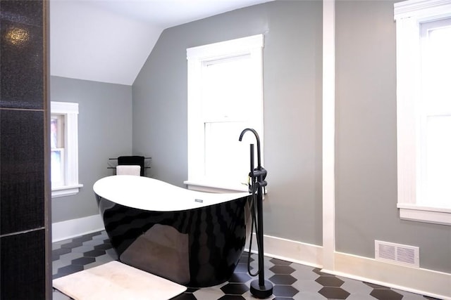 bathroom featuring a bath and lofted ceiling