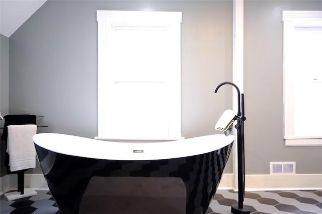 bathroom with a washtub and lofted ceiling