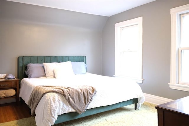 bedroom with hardwood / wood-style flooring, vaulted ceiling, and multiple windows