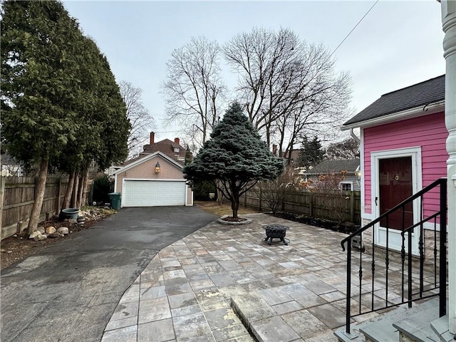 view of patio / terrace with a fire pit, a garage, and an outdoor structure