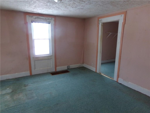 carpeted empty room featuring a textured ceiling