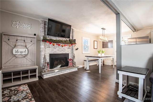 living room with wood-type flooring, a brick fireplace, a chandelier, and crown molding