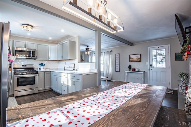 kitchen featuring a wealth of natural light, stainless steel appliances, gray cabinets, and dark wood-type flooring