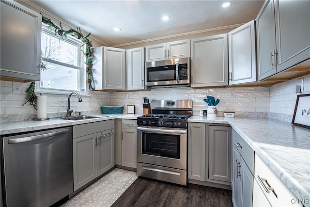 kitchen with sink, appliances with stainless steel finishes, gray cabinets, crown molding, and dark wood-type flooring