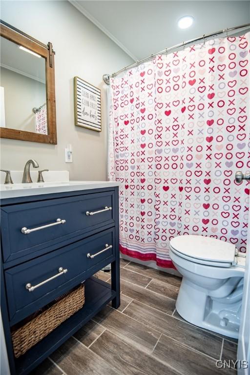 bathroom with toilet, vanity, and crown molding