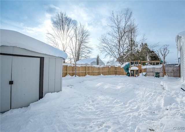 yard covered in snow with a playground and a storage shed