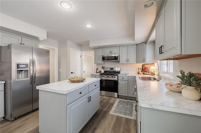 kitchen with dark wood-type flooring, a center island, gray cabinetry, appliances with stainless steel finishes, and sink