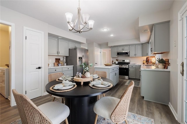 dining area featuring sink, washer and clothes dryer, an inviting chandelier, and dark hardwood / wood-style floors