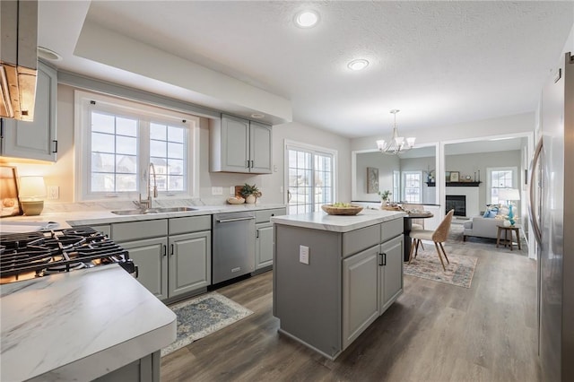 kitchen featuring gray cabinetry, appliances with stainless steel finishes, pendant lighting, a kitchen island, and sink