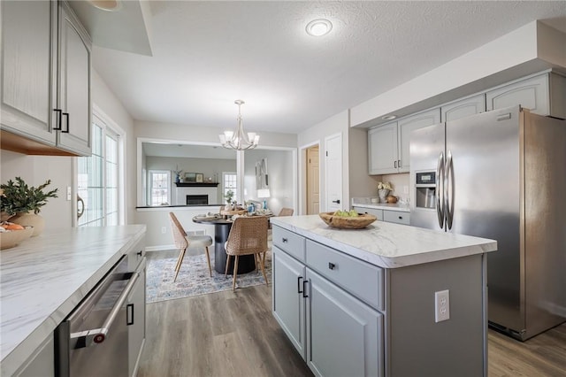 kitchen featuring a kitchen island, stainless steel appliances, gray cabinets, and decorative light fixtures