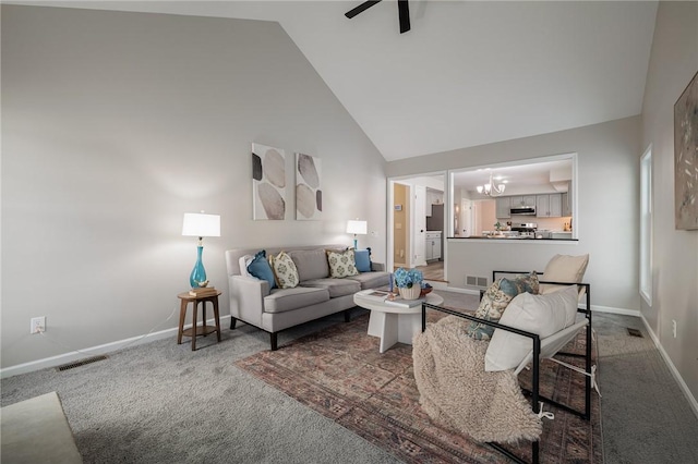 carpeted living room with ceiling fan with notable chandelier and high vaulted ceiling