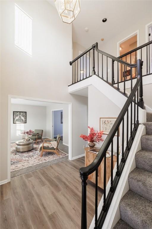 stairway featuring a high ceiling, hardwood / wood-style flooring, and a notable chandelier