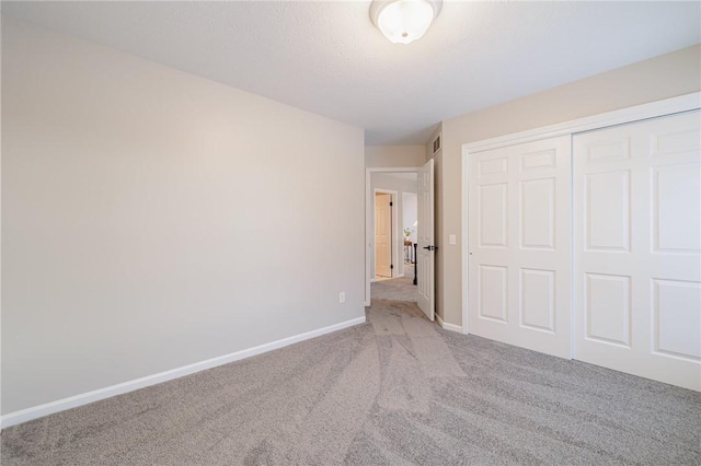 unfurnished bedroom featuring a closet and light colored carpet