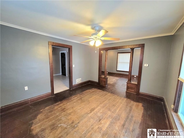 empty room featuring ornate columns, hardwood / wood-style flooring, ornamental molding, and ceiling fan