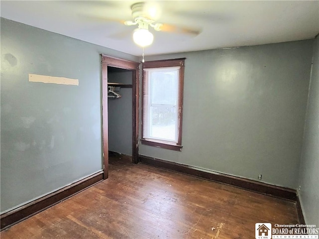 unfurnished bedroom with ceiling fan, dark wood-type flooring, and a closet