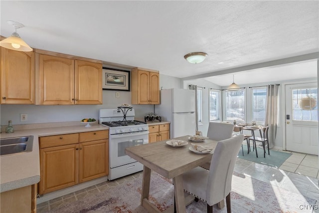 kitchen featuring sink, light tile patterned floors, white appliances, and pendant lighting