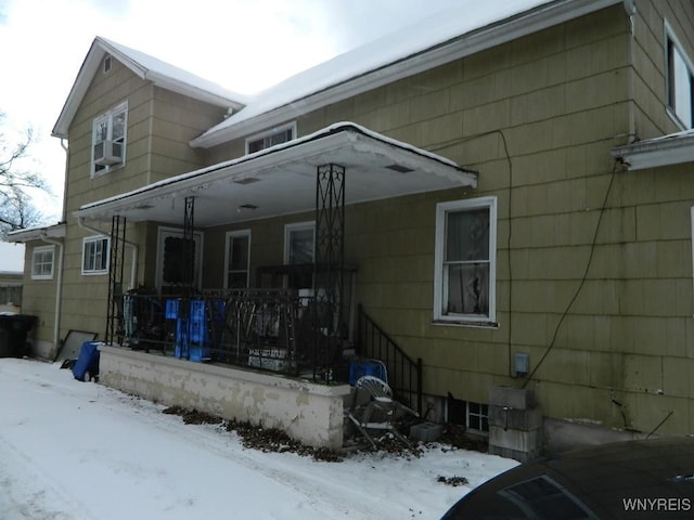 snow covered house featuring a porch