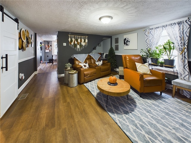 living room featuring a textured ceiling, a barn door, and hardwood / wood-style flooring