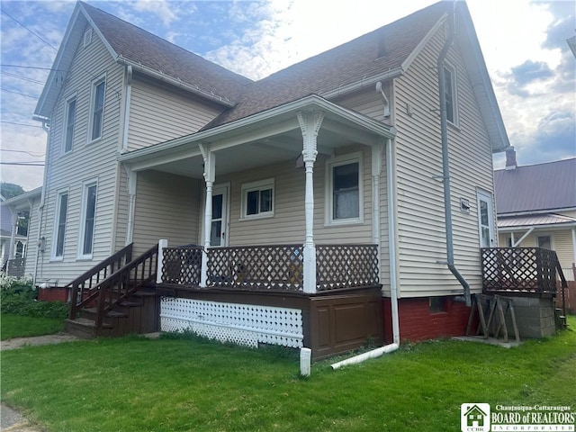 back of house featuring covered porch and a lawn