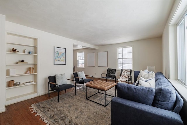 living room featuring built in shelves and dark hardwood / wood-style flooring