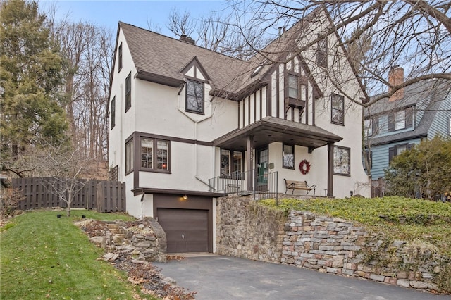 tudor home with a front yard and a garage