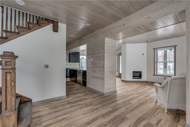 living room with wooden walls, a large fireplace, and light wood-type flooring