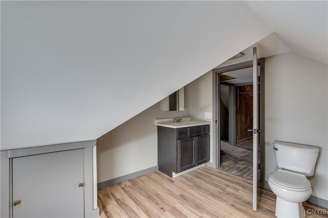 additional living space featuring lofted ceiling, sink, and light wood-type flooring