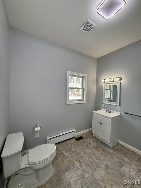 bathroom featuring baseboard heating, vanity, and toilet