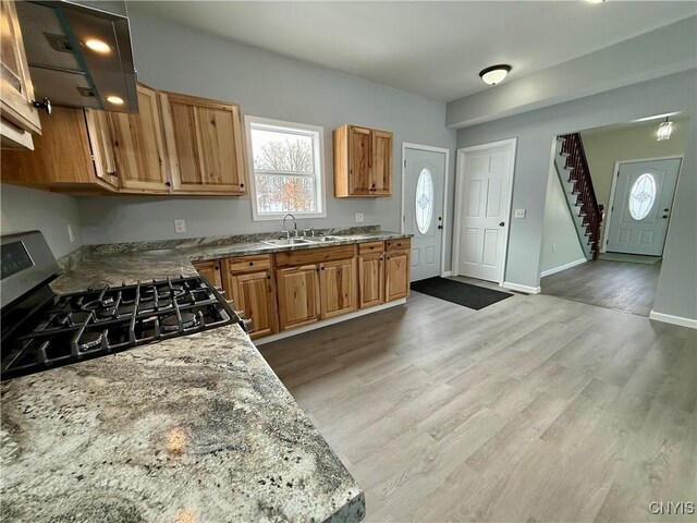 kitchen featuring hardwood / wood-style flooring, stone counters, stainless steel range with gas stovetop, and sink