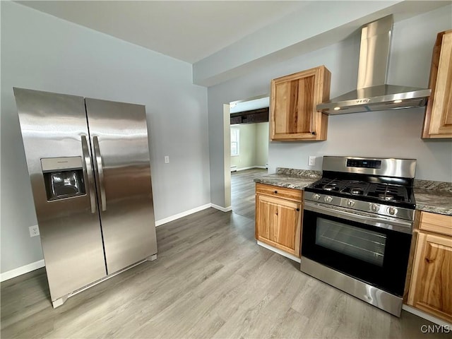 kitchen with wall chimney range hood, light hardwood / wood-style floors, and appliances with stainless steel finishes