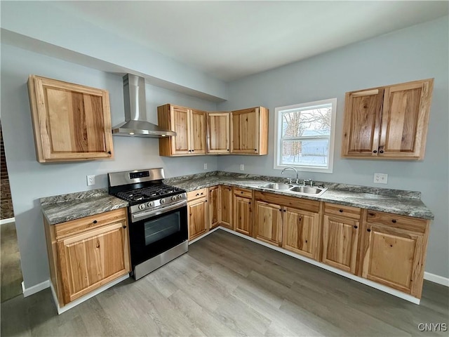 kitchen with sink, light hardwood / wood-style flooring, stainless steel range with gas stovetop, and wall chimney range hood