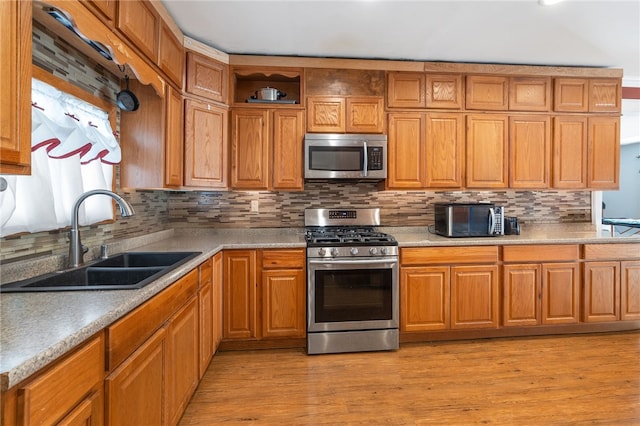 kitchen featuring sink, light wood-type flooring, backsplash, and appliances with stainless steel finishes